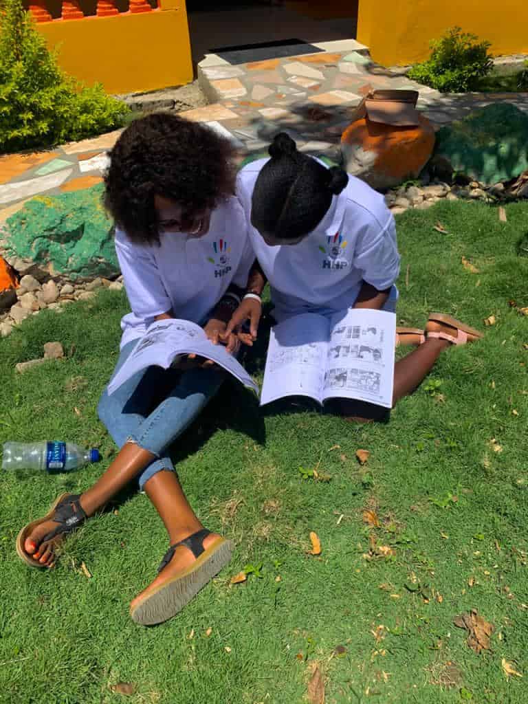 Two empowered students read books on the lawn of Happy Haitian Education
