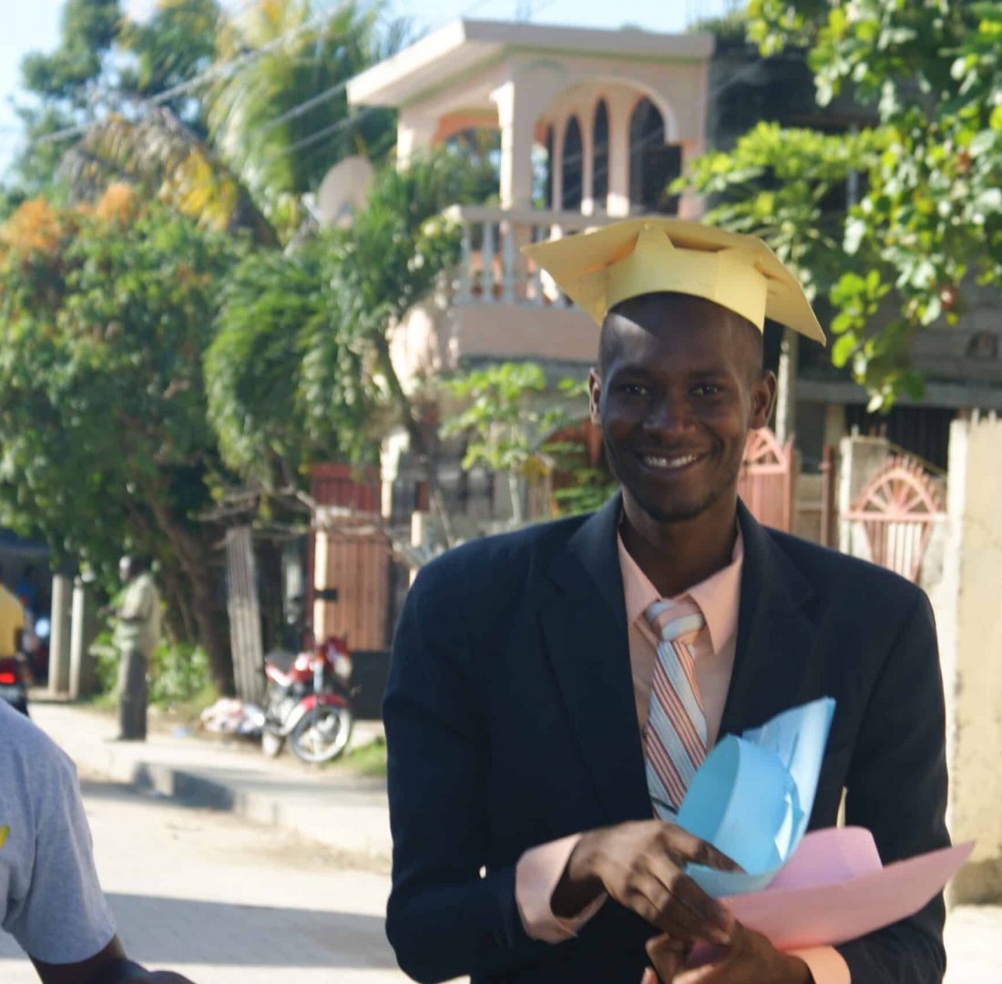 Two students prepare for graduation by distributing caps to others